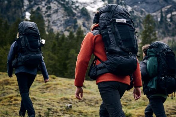 Rear view of three hikers with trekking backpacks